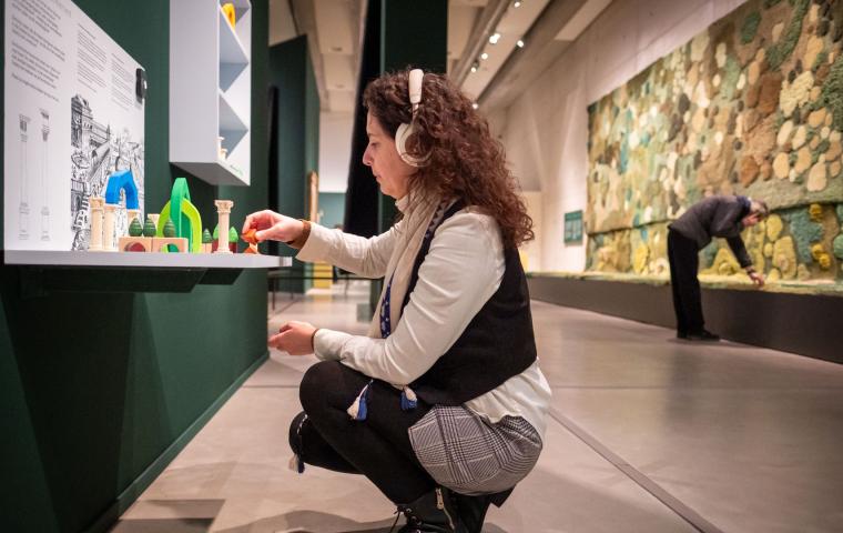 Een bezoeker met hoofdtelefoon zit op de hurken op een puzzel te maken.