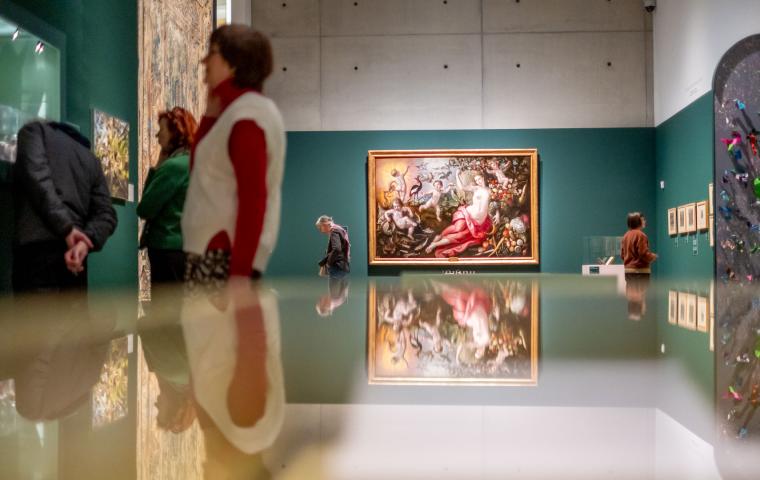 Verschillende bezoekers staan in een kleurrijke museumzaal met vele werken.