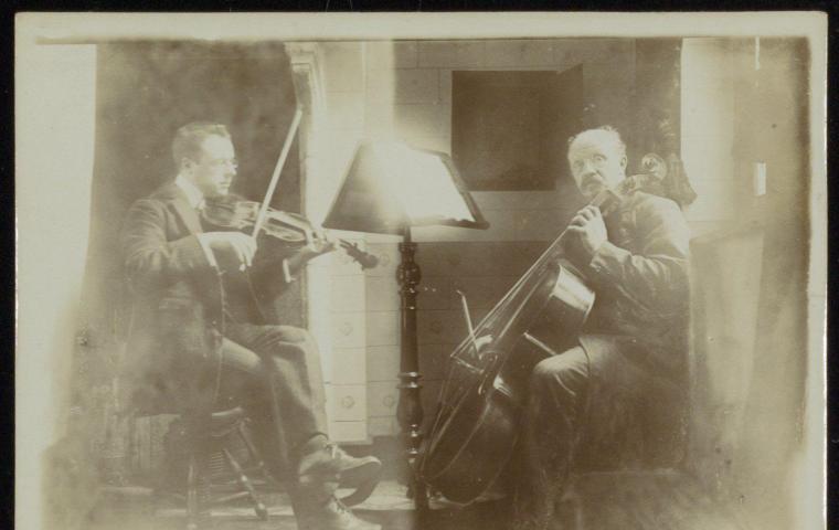 Deux hommes sont assis l'un à côté de l'autre et jouent du violon et du violoncelle