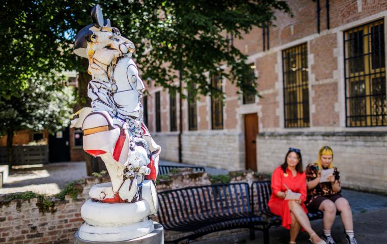 bezoekers zitten naast standbeeld in de museum tuin