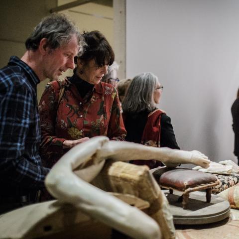 Bezoekers kijken naar een eclectische verzameling van objecten uitgestald op een tafel.