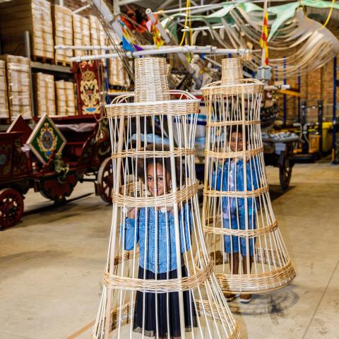 Twee kinderen dragen een rieten constructie over hun hoofd.