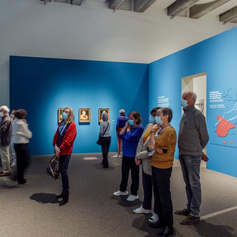 Een blauwe museumzaal met stamboom en kaart op de muren.