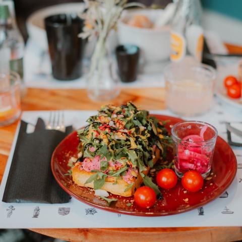 Een rood eetbord gevuld met loaded toast en tomaatjes.