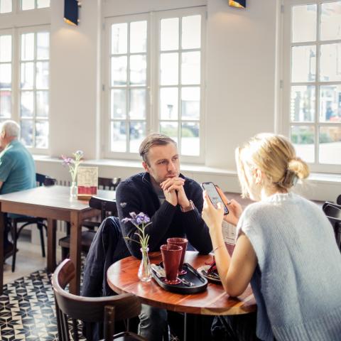 In een zonnige koffiebar zitten verschillende groepjes mensen.