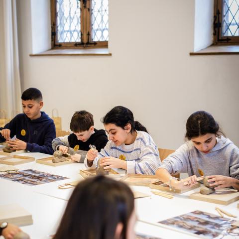 Een groep kinderen zit aan tafel en knutselt.