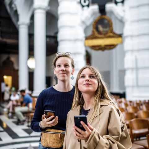Zwei Menschen stehen mit einem Smartphone in der Hand in einer Kirche und blicken nach oben.