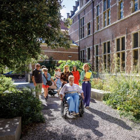 Groep bezoekers waaronder een rolstoelgebruiker in de tuin van het Hof van Busleyden.
