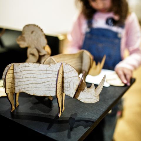 Een kind speelt met houten 3D puzzel van neushoorns en andere dieren.