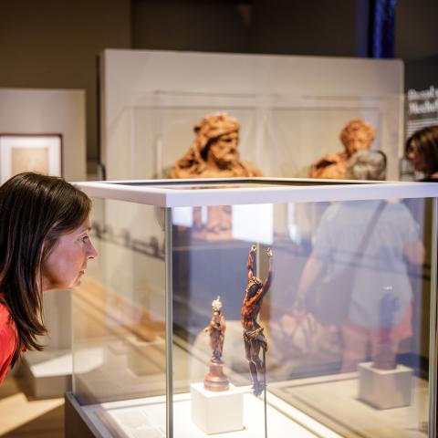 Bezoeker kijkt naar twee kleine beeldjes in een vitrine.
