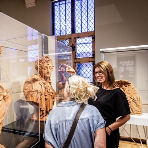 Bezoekers wijzen naar twee terracotta bustes.