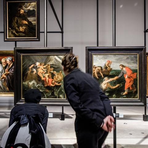 Twee mensen buigen zich voorover om een schilderij beter te bekijken.